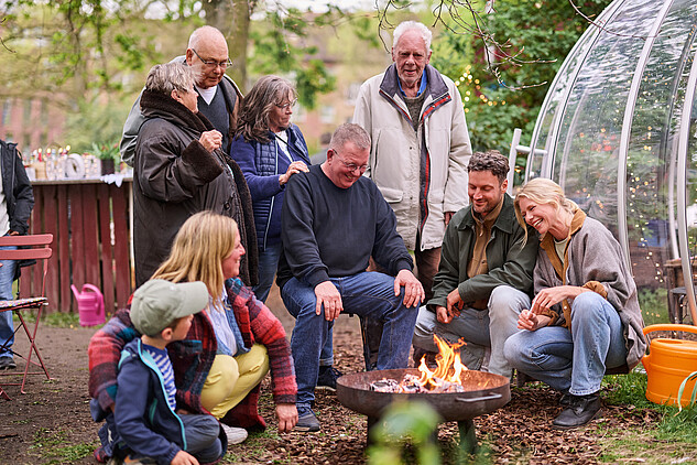 Eine Gruppe von Menschen steht um eine Feuerschale im Trinitatis Quartier Hamburg