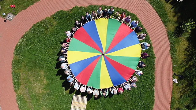 Diakonie & Bildung: Menschen mit buntem Tuch. Kirchenkreis Hamburg-West/Südholstein