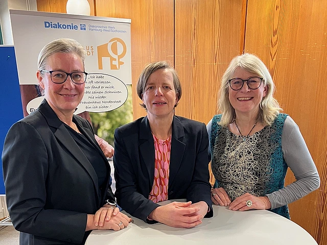 Drei Frauen an einem Stehtisch bei einer Jubiliäumsfeier eines Frauenhauses